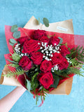 One dozen red roses with green and baby's breath.