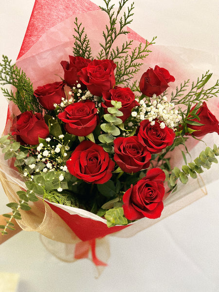 One dozen red roses with green and baby's breath.
